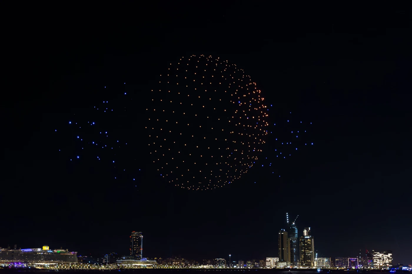 Illuminated drone formation above a city skyline at night